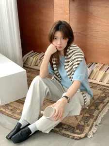 Detailed view of stylish striped knit shawl and casual top set in a cozy indoor setting.