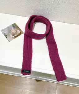 Knitted baguette scarf detail showing soft purple wool texture and brand label close up.