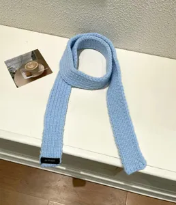 Close-up detail of a soft light blue knitted scarf, cozy solid winter accessory.