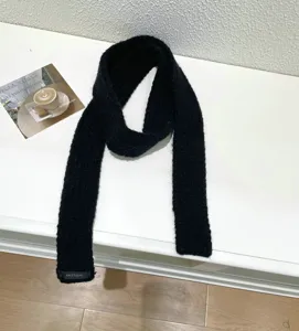 Cozy black knitted wool scarf, slender baguette neck warmer, minimalist retro winter accessory.