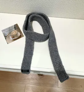 Grey knit mini scarf detail view, showing the soft texture and unique brand label design.