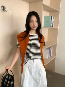 Camiseta a rayas elegante con chal de punto naranja y pantalones blancos moda para mujer.