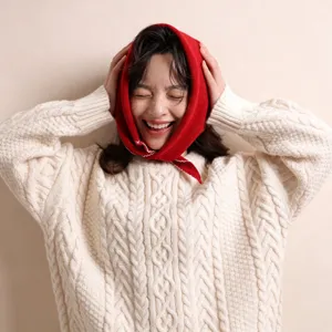 Nahaufnahme eines roten Dreieckstuchs mit Wellenkante kombiniert mit einem gemütlichen Strickpullover.