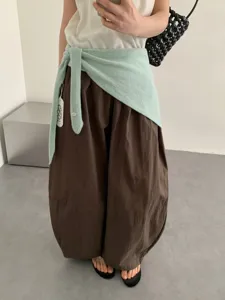 Vista detallada de bufanda chal de punto para mujer atada a la cintura con pantalones casuales.