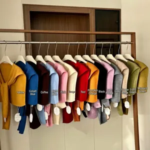 Detail van gebreide sjaal met meerdere kleurrijke tinten netjes opgehangen aan een houten kledingrek.