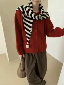 Primo piano dettagliato della sciarpa triangolare in lana a righe bianche e nere con ponpon.