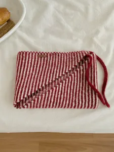 Vista dettagliata della sciarpa triangolare a maglia a righe rosse e bianche, comoda e calda.