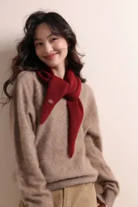 Nahaufnahme eines dunkelroten, gestrickten Dreieckschals am Model, kuschelig und warm.