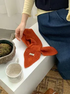 Nahaufnahme des orangefarbenen Strick-Halswärmers mit hohlem Muster und gemütlicher Textur.