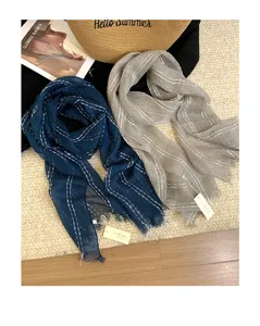 Nahaufnahme von Leinentassel-Schals in Marineblau und Grau mit Streifen, gemütlicher Stil.