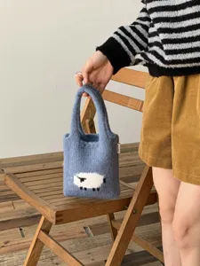 Primer plano del adorable patrón de oveja en el bolso de punto azul en detalle.