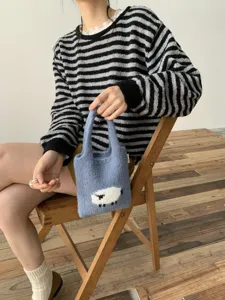 Primer plano del bolso de punto lindo con diseño de oveja esponjosa y textura suave.
