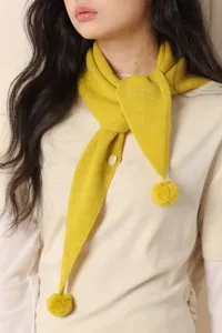 Detailed view of women's autumn winter yellow knitted triangular scarf with cute pom pom fringe.