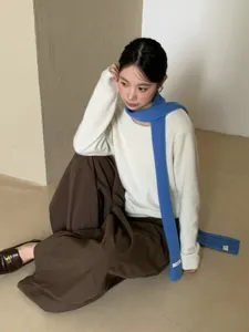Detailaufnahme eines leuchtend blauen Strickschals in einem minimalistischen Fotostudio.