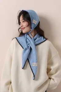Primo piano dettagliato di un set in maglia blu con cappellino e sciarpa dai dettagli traforati.