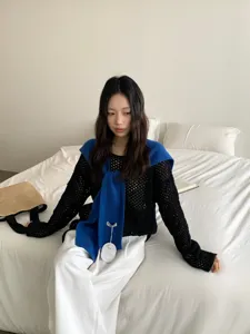 Stijlvolle zwarte mesh gebreide top gecombineerd met een chique blauwe sjaal. Herfst detail.