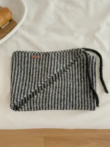 Primo piano dettagliato della sciarpa triangolare a righe in maglia con laccetto.