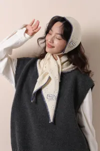 Scatto dettagliato del set cappello cuffia e sciarpa triangolare in maglia traforata blu.
