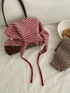 Primo piano dettagliato della elegante sciarpa triangolare a righe in maglia con lacci.