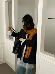 Detailopname van stijlvolle herfst winter gelaagde outfit met zwarte blazer en sjaal.