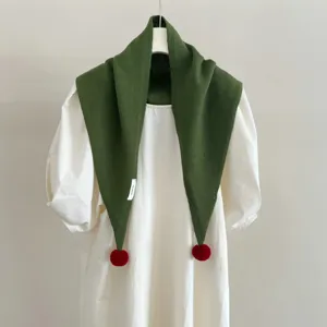 Dettaglio sciarpa triangolare in maglia verde con pon pon rossi lana inverno moda caldo