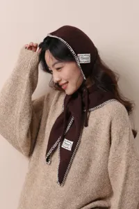 Dettaglio del set sciarpa con cappuccio in maglia marrone, trama traforata e bordi.