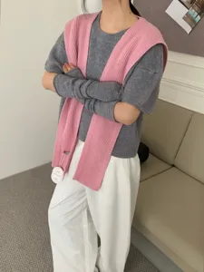 Gebreide outfit detail met een grijze top, roze sjaal en passende armwarmers.