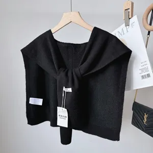 Detail shot of black knitted shawl with tie design, versatile layered shoulder accessory.