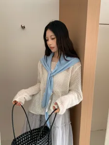 Details of Korean style hollow knit sweater and light blue shawl scarf worn by model indoors.