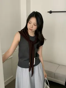 Detailed close-up view of the knitted sleeveless top paired with a brown scarf.