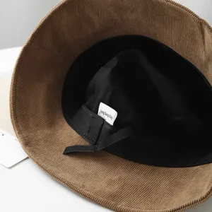 Detailed view of the brown corduroy bucket hat, showing inner black lining and label design.