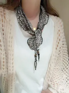 Detailed shot of a Korean style leopard print triangle scarf with chic beaded charm ties.