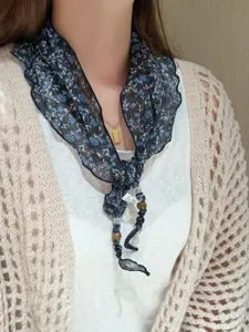 Close-up detail shot of the chic floral triangular scarf with delicate beaded strings.