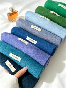Detailed view of rolled cozy wool winter scarves in vibrant colors, soft knit texture display.