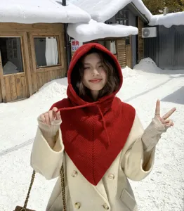 Vue détaillée d'une cagoule tricotée rouge uni avec écharpe portée dans la neige.