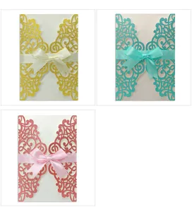 Detailed view of laser-cut lace invitation covers in gold, teal, and pink with ribbons
