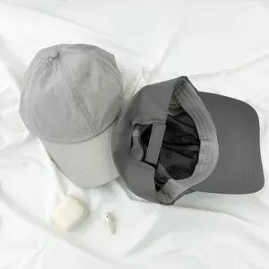 Primer plano de gorras de béisbol finas de secado rápido en gris con interior de malla ajustable.