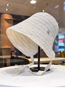 Vista detallada del sombrero de pescador con rayas, ala ancha y cintas decorativas.