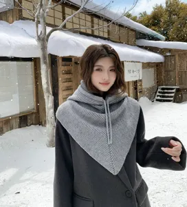 Vue détaillée de la cagoule tricotée grise avec cordon dans un paysage de neige.