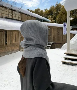 Vue détaillée de la cagoule en tricot gris douillet dans un décor enneigé en hiver.
