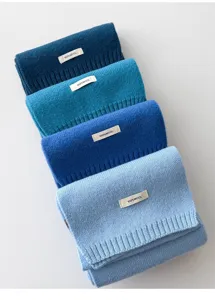 Close-up of folded winter knit wool scarves in assorted blue shades with 100% wool tags.