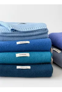 Close-up detail of luxurious blue knitted wool scarves stacked neatly, soft winter accessory.