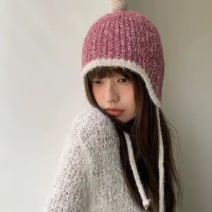 Gemütliche rosa Strickmütze mit Ohrenklappen und geflochtenen Bändern, warme Wintermütze.