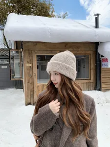 Detail shot of a soft knit beanie hat worn by a model outdoors in a winter snowy scene.