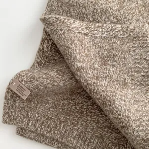 Close-up detail of cozy brown tweed knit scarf fabric, soft wool blend texture showcase.