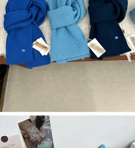Detail view of solid color knitted wool scarf with metal badge and tags fashion winter warm accessory