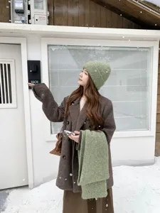 Suave bufanda y gorro de punto verde con detalle metálico para invierno acogedor.