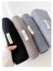 Detail view of winter solid color knit wool scarf showing soft texture and quality label.