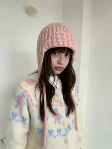 Chunky knit balaclava detail, pink cozy earflap hat closeup, warm winter knitted headwear style.
