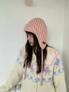 Detailed view of pink knit balaclava earflap hat, soft winter cozy warm chunky knitwear.